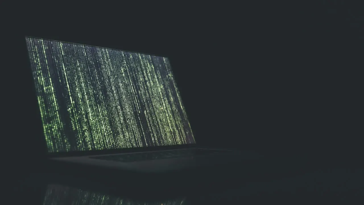Laptop scuro con codice verde luminoso sullo schermo, ambiente buio